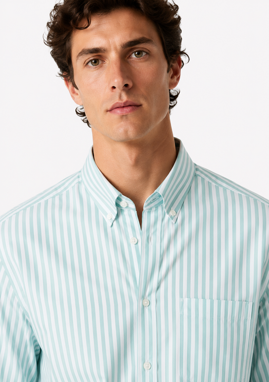 A close-up of a man wearing a light blue and white vertically striped button-down shirt against a plain light gray background.
