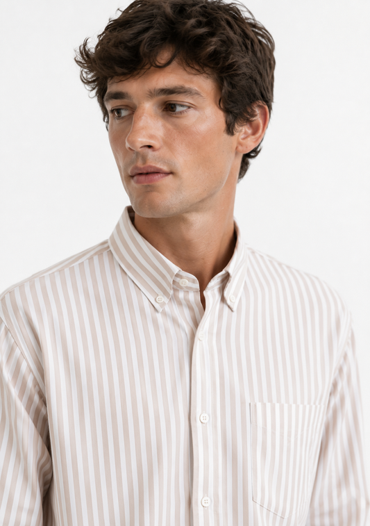 A man wearing a light beige and white vertically striped button-down shirt, shown from the chest up against a plain white background.