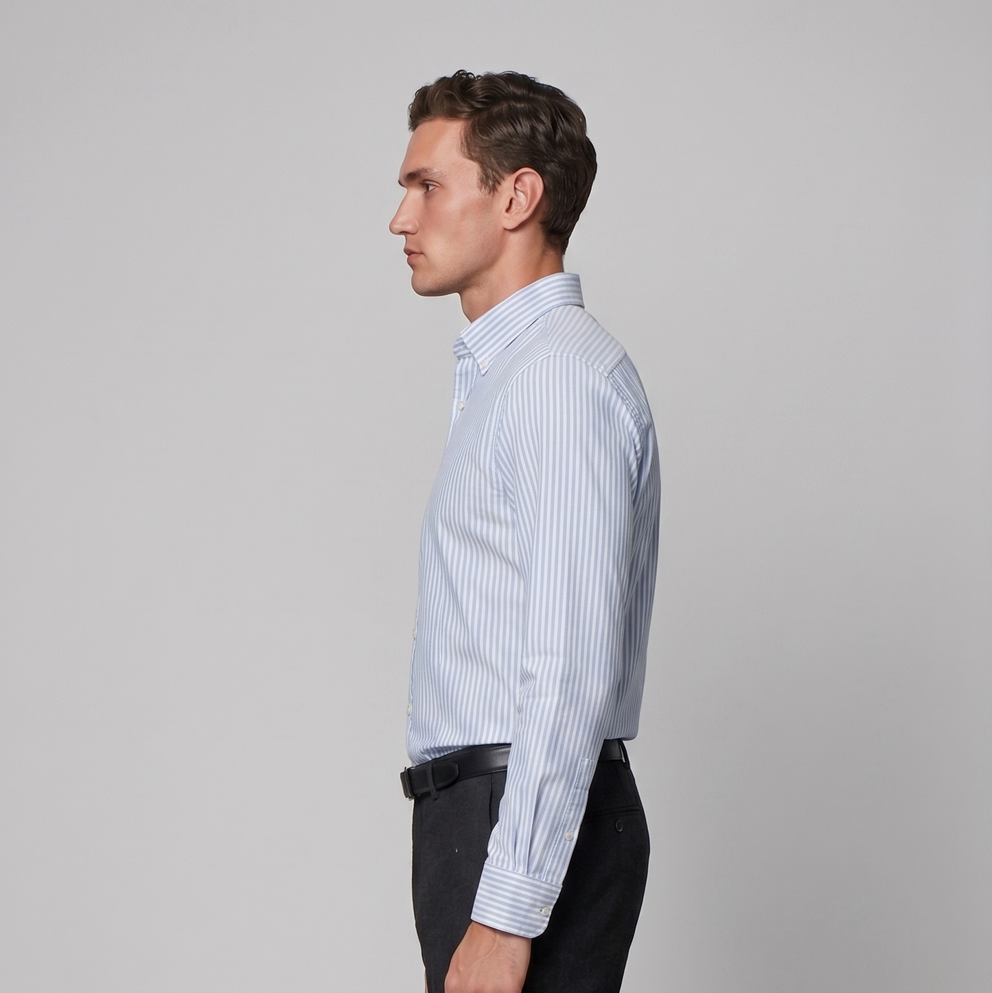 Side profile of male model wearing sky blue striped Oxford shirt